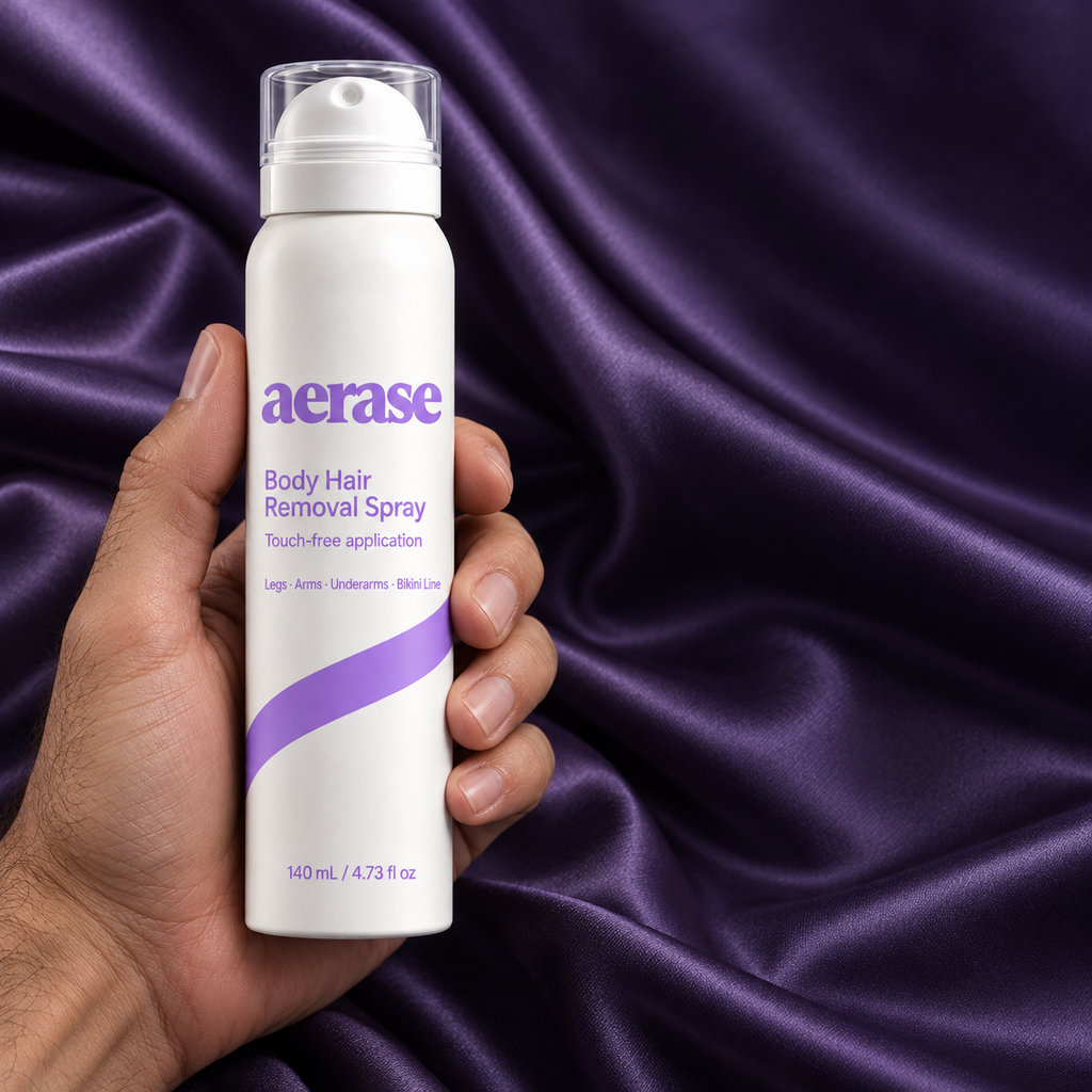 A hand holding the AERASE bottle on dark purple satin