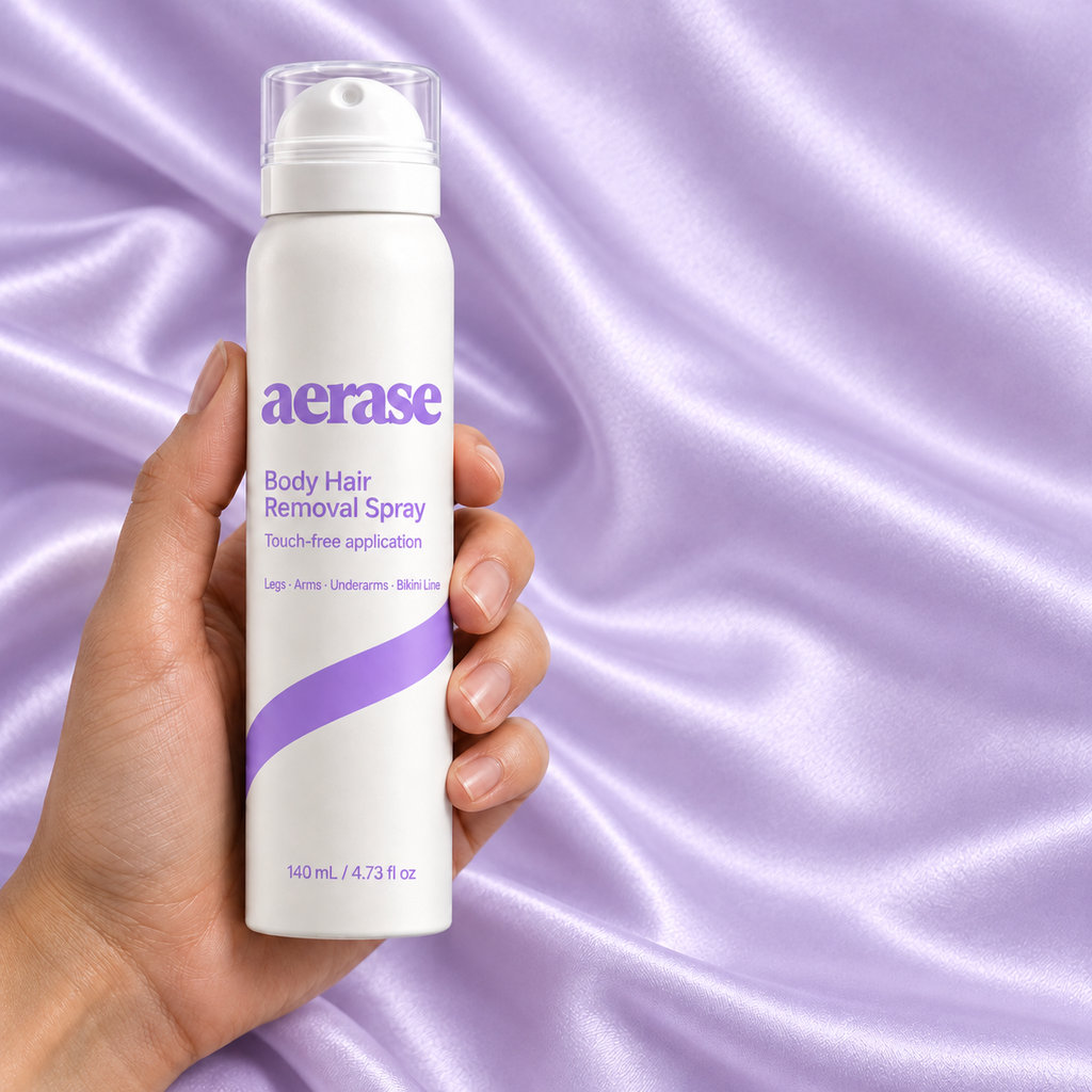 A hand holding the AERASE bottle on lavender satin